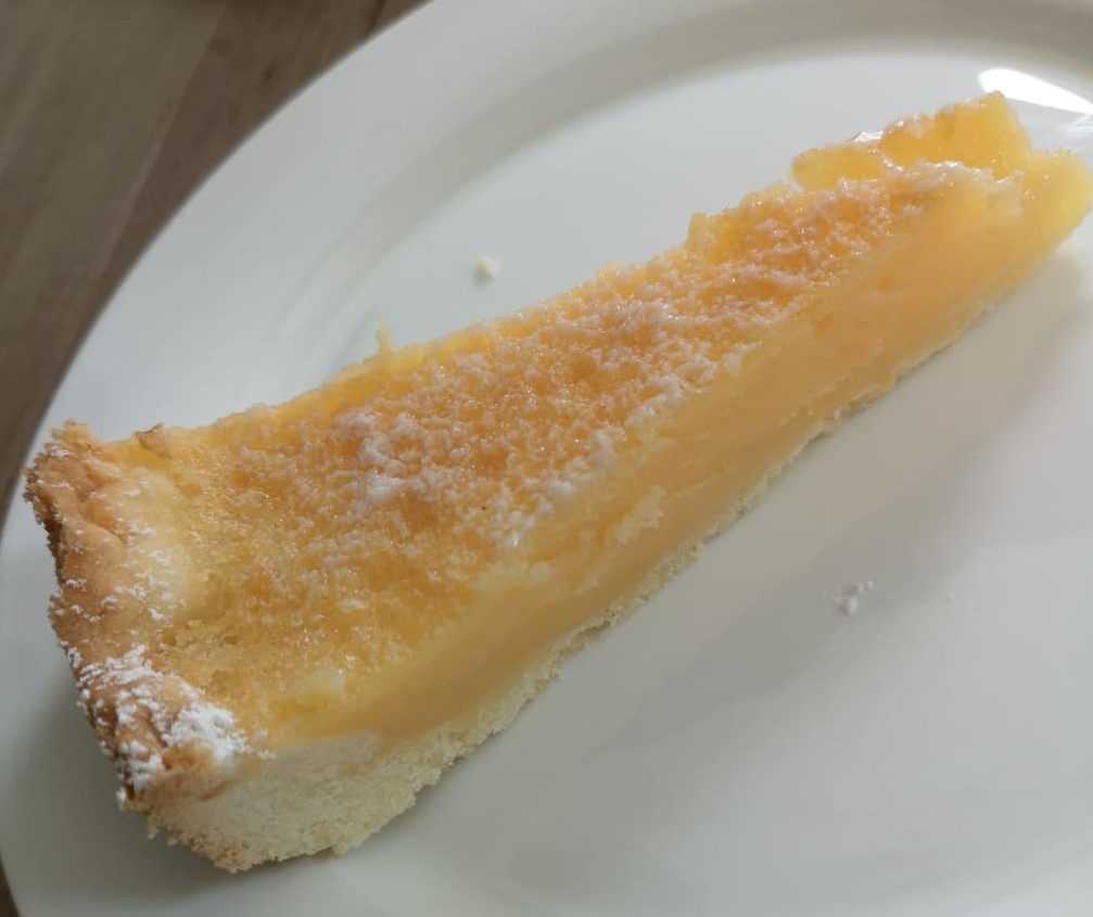 Stück Zitronen-Buttermilch-Tarte auf dem Teller